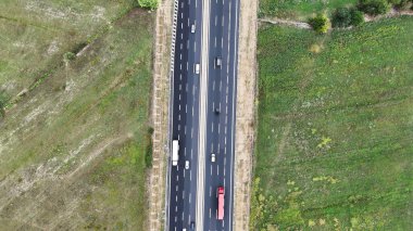 Araçların gidebileceği iki şeritli bir otoyolun genel perspektifi. Yol, farklı yönlere hareket eden arabalar ve kamyonlarla uzaklığa kadar uzanıyor.