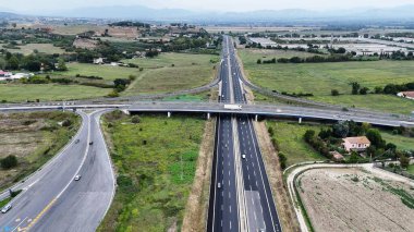 Araçların gidebileceği iki şeritli bir otoyolun genel perspektifi. Yol, farklı yönlere hareket eden arabalar ve kamyonlarla uzaklığa kadar uzanıyor.