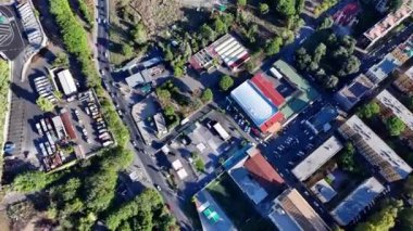 Güneşli bir günde çeşitli binaları ve işlek caddeleri olan hareketli bir şehir manzarası.