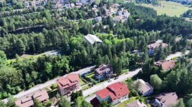 Huzurlu bir ormanın yemyeşil alanı, resim gibi bir manzarada yuva yapmış büyüleyici evlerle kusursuz bir şekilde birleşir. Güneş ışığı yeşil yaprakların arasından süzülür, kuyunun üzerine lekeli gölgeler bırakır.