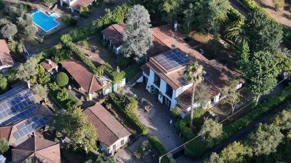 stock image Nestled in a picturesque landscape, this countryside estate features a beautiful array of buildings with solar panels, surrounded by vibrant gardens and a sparkling pool, inviting relaxation.