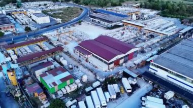 Endüstriyel ekipmanları, kamyonları ve büyük miktarlarda mermer levhaları gösteren bir mermer işleme fabrikasının havadan görüntüsü.