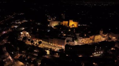 Gece vakti aydınlık bir ortaçağ kasabasında dönen bir kamera.