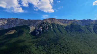 İnsansız hava aracı kayalık bir dağın üzerinden uçuyor, bulutlar gökyüzünde.