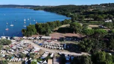 Yelkenli ve katamaranların birkaç hava görüntüsü bir gölün yanındaki kayıkhanede karada dinleniyor.