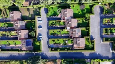 Güneş bir yerleşim bölgesinin üzerinde hareket ediyor, evlerin ve bahçelerin üzerine uzun gölgeler bırakıyor.