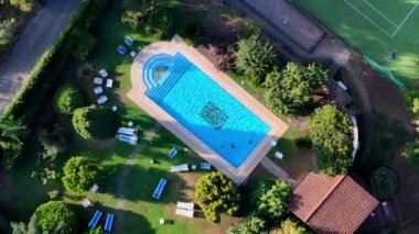 Turistler güneşli bir günün keyfini çıkarıyorlar. Lüks bir tatil köyünde yüzüp güneşleniyorlar.