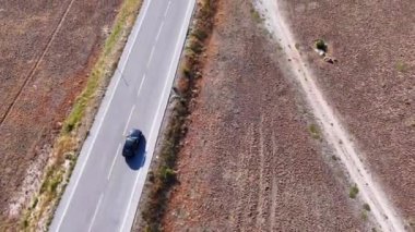 Siyah araba ormanla çevrili bir dağ yolunda ilerliyor.