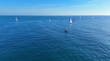 Mavi gökyüzüyle güzel bir günde yelkenliler açık denizde yarışıyor.