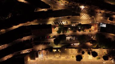 Gece aydınlık bir şehir parkına bakan kamera, insanların sıcak yaz akşamının tadını çıkardığını gösteriyor.