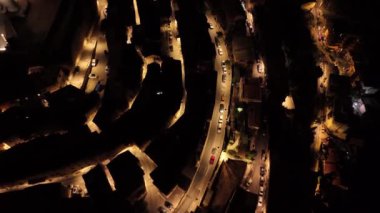 Geceleri hareketli şehir sokaklarını yakalıyor, kıvrımlı yolları ve parlayan sokak ışıklarını gösteriyor. Şehir yaşamına yukarıdan büyüleyici bir bakış.