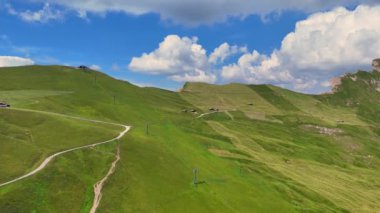 Beyaz bulutlar, yeşil bir dağın üzerinde mavi bir gökyüzünde hareket ediyor.