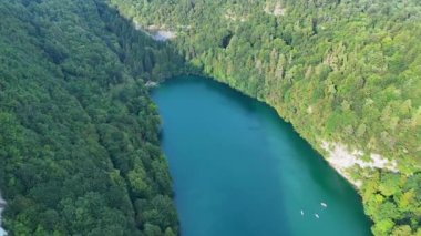Kamera, yemyeşil bir ormanla çevrili turkuaz bir göl üzerinde çekim yapar ve çevresindeki doğal sakinliği ve benzersiz şeklini gözler önüne serer.