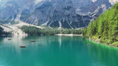 Turistler güneşli bir günün tadını çıkarıyorlar dolomit dağlarının manzarasıyla Braies Gölü 'nün turkuaz suyunda kürek çekiyorlar.