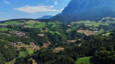 Kamera yemyeşil bir vadide, arka planda dağlar var.