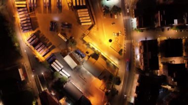 Birçok otobüs gece bir depoya park edilir, sokak lambalarıyla aydınlatılır.
