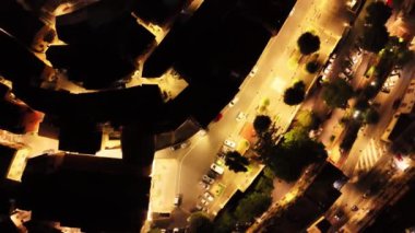 Kamera küçük bir kasabada dönüyor, geceleri sokak ışıklarını gösteriyor.