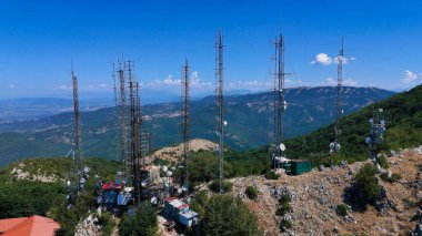 Doğanın kalbinde yer alan bir iletişim kuleleri topluluğu nefes kesen bir dağ sırasının arka planına karşı belirgin bir şekilde yükseliyor. Gözden kaçan yemyeşil vadiler, kulelerin bir karışımı