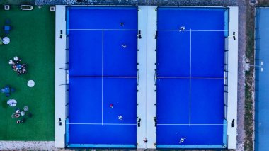 Açık mavi gökyüzünün altında oyuncular yeteneklerini açık mavi tenis kortlarında sergileyerek enerji ve rekabetle dolu dinamik bir atmosfer yaratıyorlar. Mahkemeler, iyi korunan bir yer.