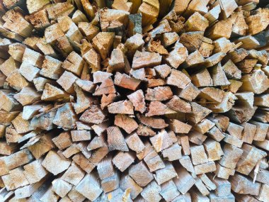 Düzgünce kesilmiş odun yığınları dairesel bir düzende dizilir ve dokulu yüzeyleri sergilenir. Sıcak melodiler ve karmaşık detaylar, serin gecelere hazırlık ve doğa hissini uyandırıyor..