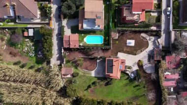 Göz kamaştırıcı bir hava manzarası, özel evler, yemyeşil bahçeler ve güneş ışığında güneşlenen ışıl ışıl bir yüzme havuzu içeren canlı bir yerleşim alanı yakalıyor. Yeşillik huzurlu bir yaşam tarzını işaret ediyor..