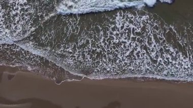 Altın saat, kumsalda ılık bir parıltı salıyor. Beyaz köpüklü dalgalar kumlu kıyıya doğru yavaşça süzülüyor. Doğa ritmi deniz kenarında sakin bir çekilme sunar..
