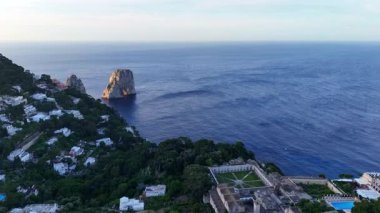 Nefes kesici bir manzara, yumuşak sabah ışığı altında canlı yeşillikler ve beyaz villalar tarafından çerçevelenmiş sakin denizi kucaklayan kayalık uçurumları yakalar. Doğanın güzelliği uyum içinde ortaya çıkar..