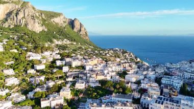Capri Adası 'nın yamaçlarından süzülen canlı evler yemyeşil ve büyüleyici mavi denizin arasına yerleşmiş. Manzara aydınlık bir öğleden sonra sükunet saçar..