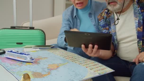 世界中のクルーズ船で夏休みの旅行を屋内で地図で計画し 議論するデジタルタブレット上でオンラインでネットワーキングシニア観光客の手の閉じる — ストック動画