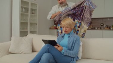 Sevecen, olgun bir adam battaniyeye sarılmış sevimli yaşlı bir kadınla çevrimiçi dijital tablete bakmakla, sevgi, ilgi ve güçlü bir bağ göstermekle meşgulken emekli çift yurt odasında dinleniyor..