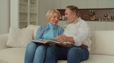 Neşeli, çekici, son sınıf öğrencisi ve neşeli, olgun bir adam kanepeye oturmuş, aile fotoğrafı albümü izliyor, mutlu ve komik anları paylaşıyor ve hatırlıyor..