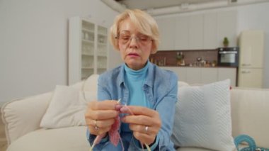 Gözlüklü, çekici, emekli bir kadının portresi. Elinde örgü iğneleri, örgü örme hobisi ve evde boş vakit geçirirken sıcak el yapımı kıyafetler üretme zevki..
