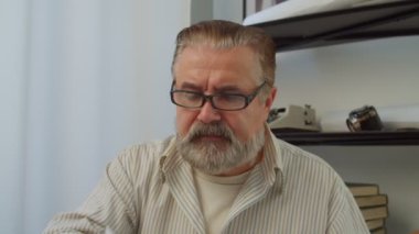 Gözlüklü, düşünceli, sakallı, olgun bir adamın portresi. Bir ucu ağızda, düşünceli bir ifadeyle yan yana bakıyor. Sorunlar ve çözümler üzerine kafa yoruyor..