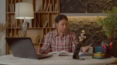 Konsantre olmuş başarılı Afrikalı Amerikalı iş kadını çevrimiçi dizüstü bilgisayarla ağ kuruyor, finansal haritaları analiz ediyor ve merkez ofiste çalışırken iş projelerini planlıyor..