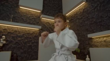 Beyaz kimono eğitimi almış, çok kültürlü, çok kültürlü karateka 'nın düşük açılı görüntüsü. Karate yumruk teknikleri, kapalı alanda kendini adama ve motivasyon gösterme..