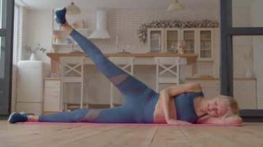 Etkin motivasyonlu sportif fitness son sınıf öğrencisi kadın yoga minderi, kas kasları, kalça kasları ve sırt kasları üzerinde egzersiz yükselterek evdeki çekirdek dayanıklılığını ve istikrarını artırıyor..