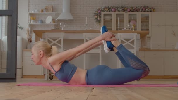 在健身垫上练习瑜伽弓姿 伸展腹部 臀部前部 后背和臀部肌肉时 积极的 有吸引力的 适合成熟女性的运动服 — 图库视频影像