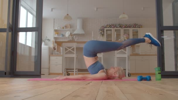 运动健美的运动健美的老年女子在健身垫 伸展脊柱 肩腿肌肉 提高柔韧性和室内核心力量方面做瑜伽犁地姿势 — 图库视频影像