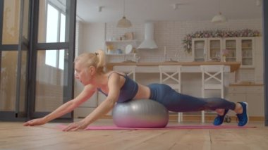 Aktif, sağlıklı bir yaşam tarzı spor kıyafetleri içinde son sınıf güzel bir kadın omuz kaldırma egzersizi yapıyor, vücudunun üst kısmını, omuz ve göğüs kaslarını evde güçlendiriyor..