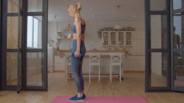 Aktif giyimde kararlı çekici fitness üst düzey kadın çapraz antrenman yapıyor, dambıl egzersizi ile ters hamle yapıyor, iç odalarda vücut, kalça ve bacak kaslarını güçlendiriyor..