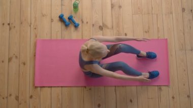 Evde spor antrenmanı yaparken karın kasları, sırt ve kalça kasları güçlendirip mekik egzersizi yapan kararlı, çekici sportif fitness son sınıf kadınlarının en iyi görüntüsü..