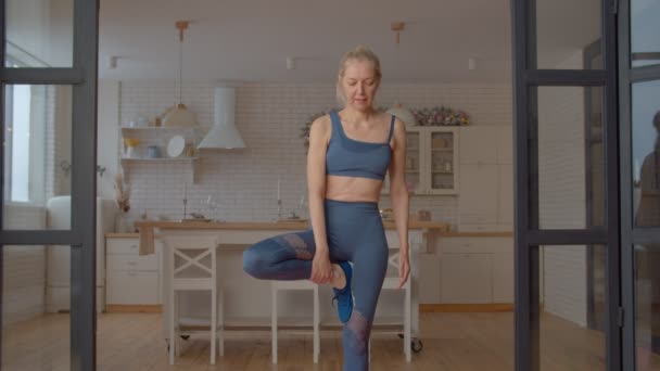 在室内锻炼中 迷人的运动适合站在瑜伽树上的成熟女性 能伸展双脚 增强核心肌肉 改善身体平衡 — 图库视频影像