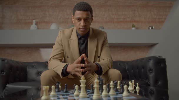 成功したハンサムなアフリカ系アメリカ人男性エグゼクティブ移動チェスの作品チェスボードとチェックメイト対戦相手ゲーム中に オフィスで自信とポジティビティを表現 — ストック動画