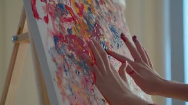 Close-up of teenage hands finger painting colorful picture on canvas, expressing creativity, imagination and fantasy.