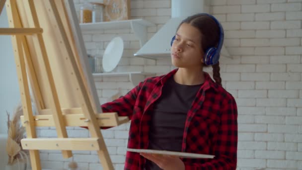 Positive Attractive Hispanic Teenage Girl Painter Listening Music Wireless Headphones — Αρχείο Βίντεο