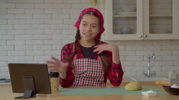 肯定的な美しいヒスパニック系の10代の女の子のウェブインフルエンサーは デジタルタブレットを使用してライブストリーミング食品Vlogをストリーミング 家庭用キッチンで自家製クッキーのレシピについてオンライン観客と共有 — ストック動画