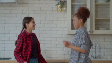 Saçları örgülü neşeli, sevimli, çok kültürlü ergen bir kızın portresi. Afro-Amerikan annesinin keyfi yerinde. Mutfakta mutlu bir şekilde dans ediyor..