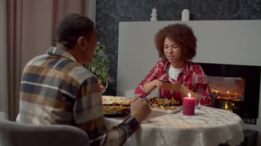 Happy charming black female enjoying tasty canapes with salmon, prepared by loving man while united African American couple celebrating valentines day and eating romantic dinner at home.