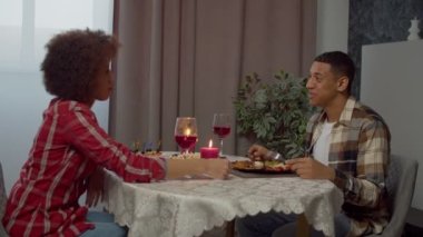 Affectionate attractive black couple enjoying dinner in candlelight, sharing beautiful moments and holding hands, showing love, happiness and strong relationship while having romantic date indoors.