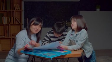 Neşeli, yaratıcı, şirin, ilkokul kızı. Sevecen bir anneye resim çiziyor. Neşeli, birleşik bir aile, boş zamanlarının tadını çıkarıyor ve ev odasında eğleniyor..